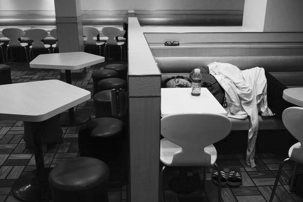 A man sleeps at a 24-hour McDonald's restaurant in Hong Kong, China November 10, 2015. A large number of homeless people sleeping on the street has long been been a problem in Hong Kong mainly due to its high rent and soaring property. In recent years, McDonald's 24-hour fast food shops opening all over the city have become popular alternatives for people, know as McRefugees or McSleepers, to spend the night in a safer and more comfortable way than on the street. Picture taken on November 10, 2015. REUTERS/Tyrone Siu - RTS6EXQ