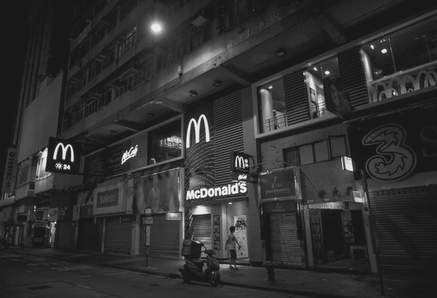  man walks past at a 24-hour McDonald's restaurant in Hong Kong, China November 10, 2015. A large number of homeless people sleeping on the street has long been been a problem in Hong Kong mainly due to its high rent and soaring property. In recent years, McDonald's 24-hour fast food shops opening all over the city have become popular alternatives for people, know as McRefugees or McSleepers, to spend the night in a safer and more comfortable way than on the street. Picture taken on November 10, 2015. REUTERS/Tyrone Siu - RTS6F1C