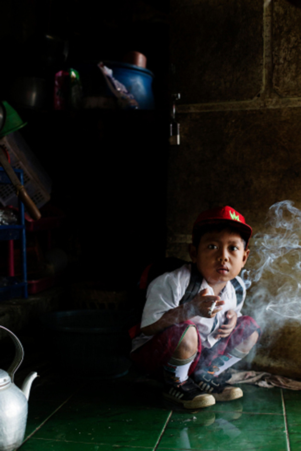 Dihan Muhamad, who used to smoke up to two packs of cigarettes a day before cutting down, poses for a photo as he has his first cigarette at 7AM at his home before he attends his first grade class in his village near the town of Garut, Indonesia on February 10, 2014.
